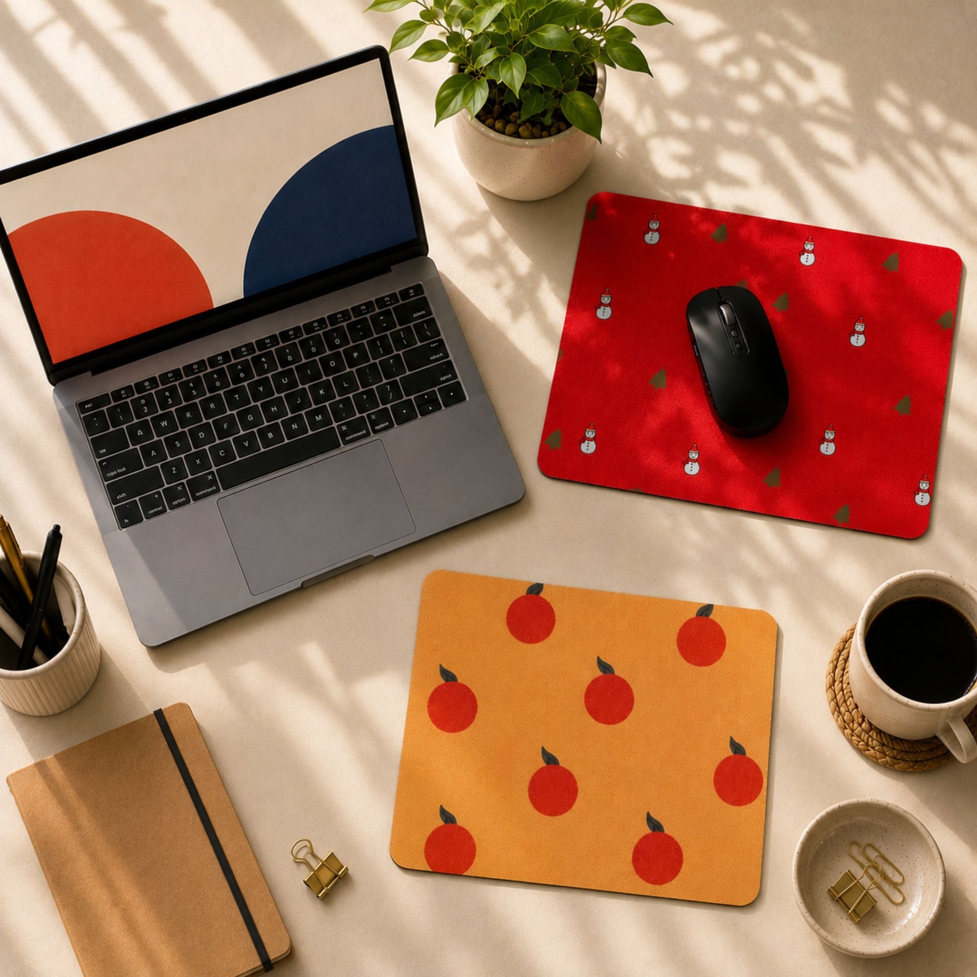 Red and orange coloured mousepads in a table setting with laptop, book and coffee