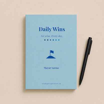Blue book titled 'Daily Wins' with a pen on a beige background