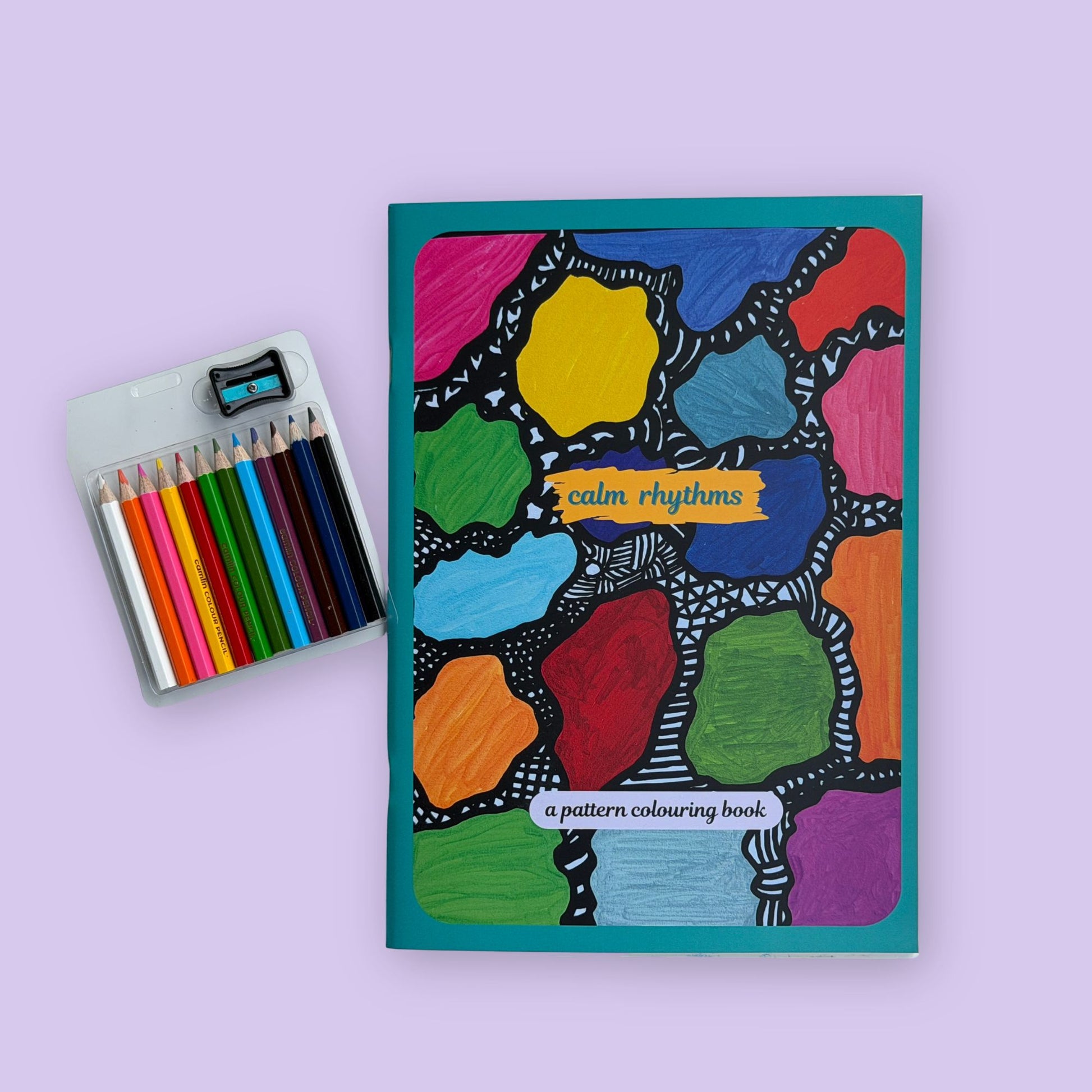Colorful patterned coloring book with colored pencils on a light purple background