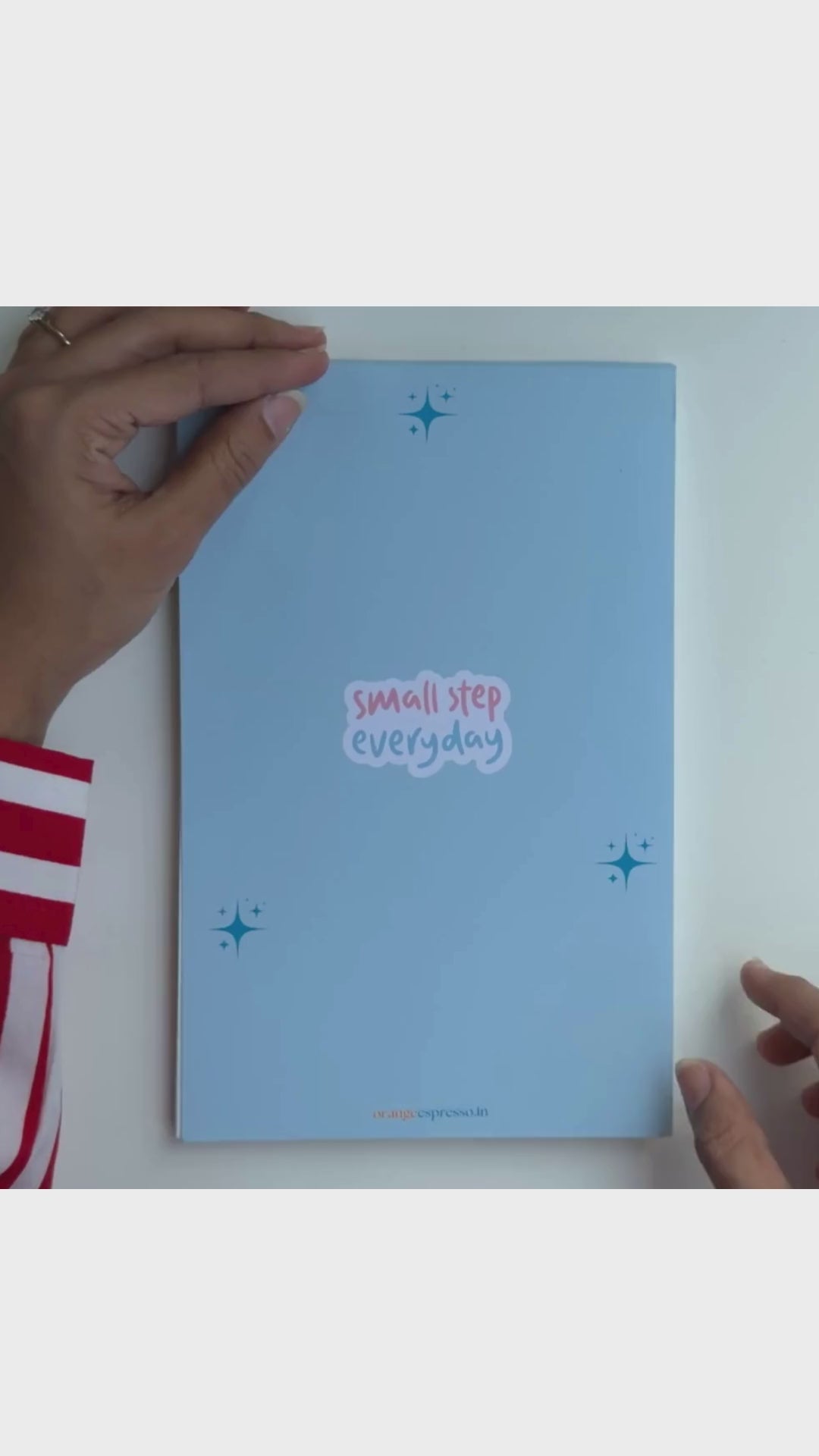 A walk around video of 'Small Steps Everyday', a daily to-do notepad from Orange Espresso. The front cover is blue and the inner pages are light blue.